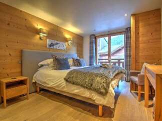 Experience cozy mountain living in this charming bedroom, featuring warm wood-paneled walls and a plush, inviting bed.