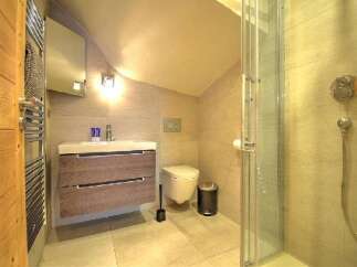 This modern bathroom features a sleek vanity with ample storage, a wall-mounted toilet, and a spacious glass-enclosed shower.