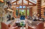 Experience rustic luxury in this stunning log cabin living room, featuring a grand stone fireplace and soaring vaulted ceilings with exposed wooden beams.