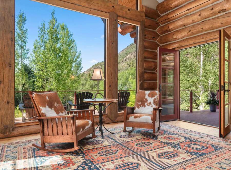 Experience rustic charm in this log cabin living area, featuring cozy rocking chairs with cowhide cushions and a large area rug.