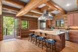 Experience rustic charm in this log cabin kitchen, featuring a large granite island with a gas stovetop and seating for four.