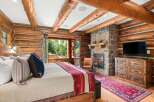 Experience rustic luxury in this charming log cabin bedroom, featuring a cozy fireplace and stunning mountain views.