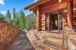 Experience rustic charm with this stunning log cabin, featuring a grand entrance with double doors and a stone pathway leading to the front porch.