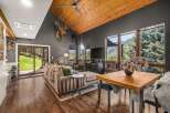 Experience breathtaking mountain views from this stunning living room, featuring a vaulted wood-paneled ceiling and a cozy fireplace.