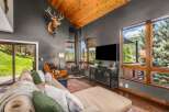 Experience rustic luxury in this stunning living room, featuring a vaulted wood-paneled ceiling and a majestic mounted elk.