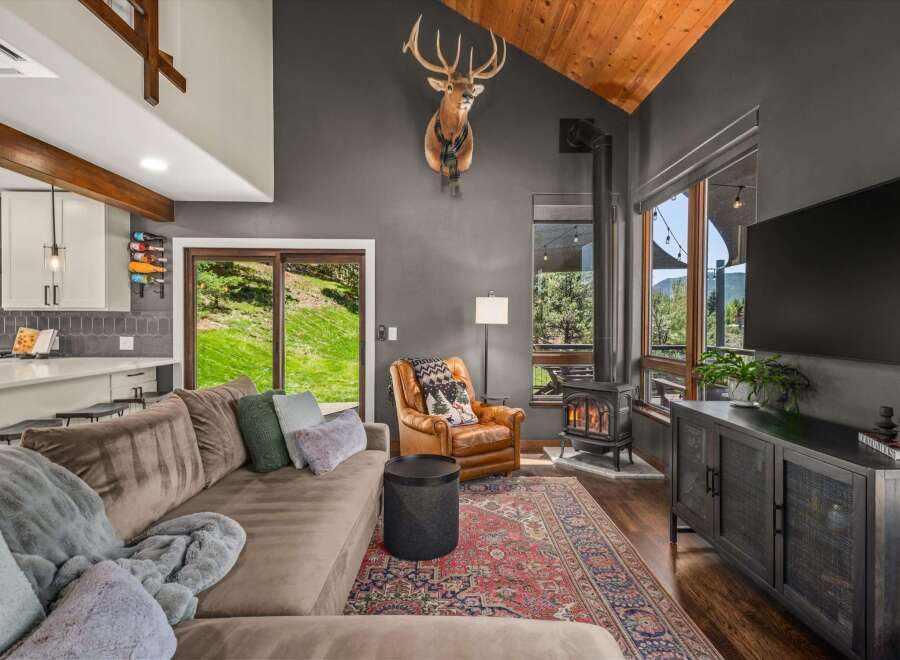 Experience rustic charm in this inviting living room, featuring a cozy sectional sofa and a striking mounted deer head.