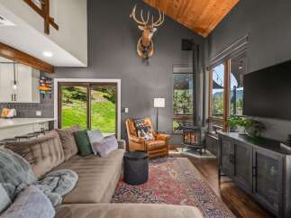 Experience rustic charm in this inviting living room, featuring a cozy sectional sofa and a striking mounted deer head.