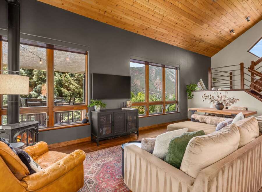 Experience breathtaking mountain views from this stunning living room, featuring a cozy fireplace and a large sectional sofa perfect for relaxation.