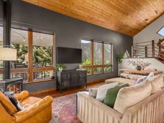 Experience breathtaking mountain views from this stunning living room, featuring a cozy fireplace and a large sectional sofa perfect for relaxation.
