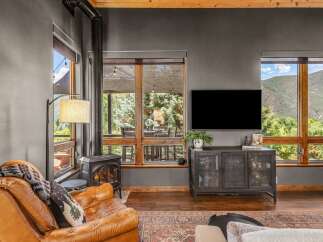 Experience cozy living in this mountain retreat, featuring a rustic wood-burning stove and a plush leather armchair perfect for relaxing evenings.
