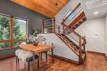 Experience modern mountain living in this stunning home featuring a sleek dining area with a wooden table and plush seating, complemented by large windows offering breathtaking views of the surrounding nature.