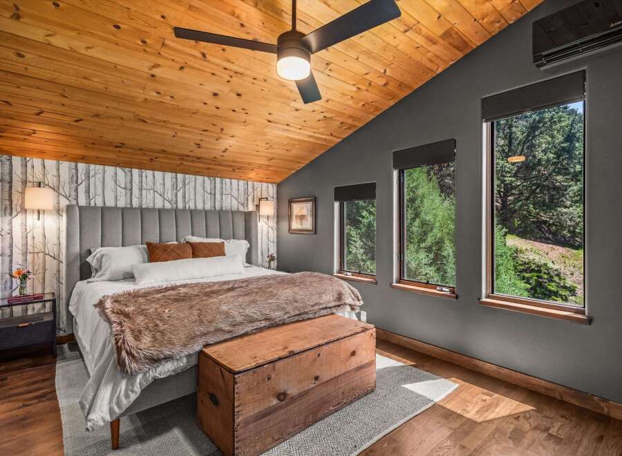Experience rustic charm in this inviting bedroom, featuring a vaulted wood-paneled ceiling and a cozy atmosphere.