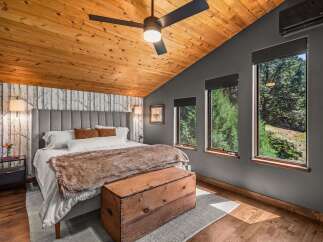 Experience rustic charm in this inviting bedroom, featuring a vaulted wood-paneled ceiling and a cozy atmosphere.