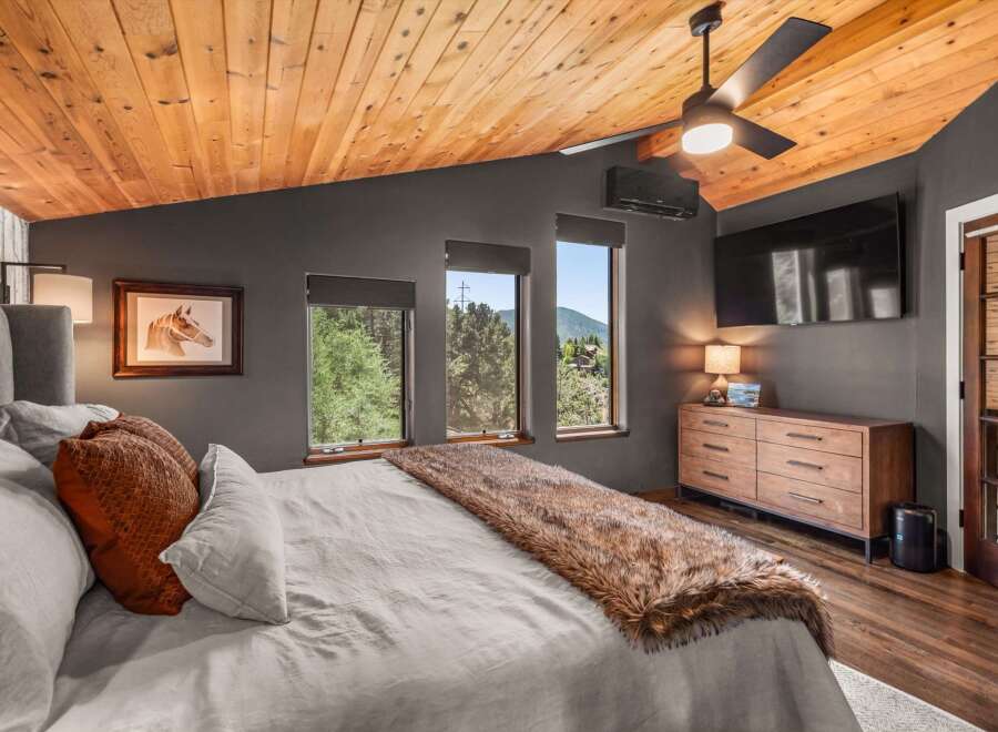 Experience rustic luxury in this stunning bedroom featuring a vaulted wood-paneled ceiling and a cozy faux fur throw on the bed.