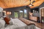 Experience rustic luxury in this stunning bedroom featuring a vaulted wood-paneled ceiling and a cozy faux fur throw on the bed.