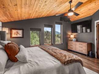 Experience rustic luxury in this stunning bedroom featuring a vaulted wood-paneled ceiling and a cozy faux fur throw on the bed.