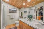 This beautifully appointed bathroom features a vaulted wood-paneled ceiling and a spacious vanity with dual sinks.