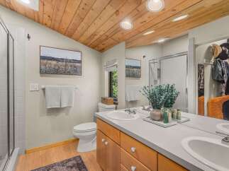 This beautifully appointed bathroom features a vaulted wood-paneled ceiling and a spacious vanity with dual sinks.