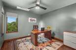 This home office features a stylish wooden desk with a laptop and a vase of sunflowers, complemented by a comfortable leather chair with a plaid throw.