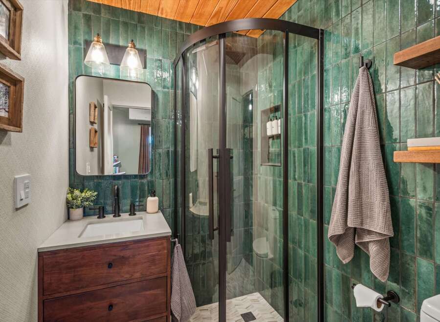 Experience luxury in this stunning bathroom featuring a modern vanity with a dark wood cabinet and a sleek countertop.
