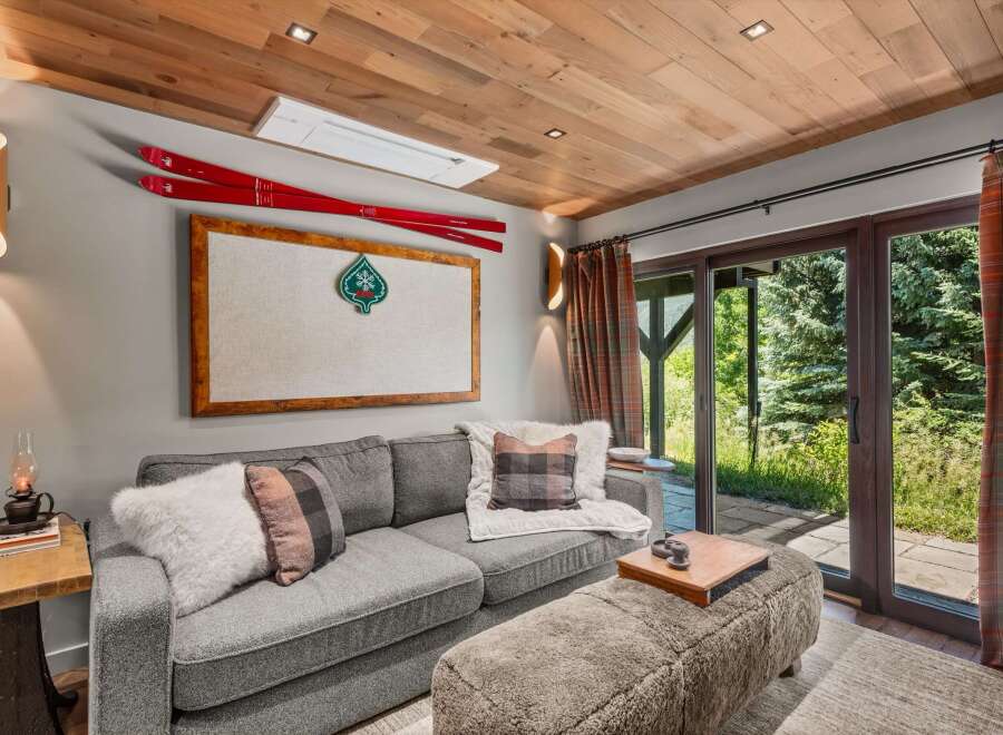 Experience cozy mountain living in this inviting living room, featuring a plush grey sofa adorned with plaid and faux fur pillows.