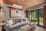 Experience cozy mountain living in this inviting living room, featuring a plush grey sofa adorned with plaid and faux fur pillows.