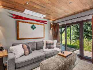 Experience cozy mountain living in this inviting living room, featuring a plush grey sofa adorned with plaid and faux fur pillows.