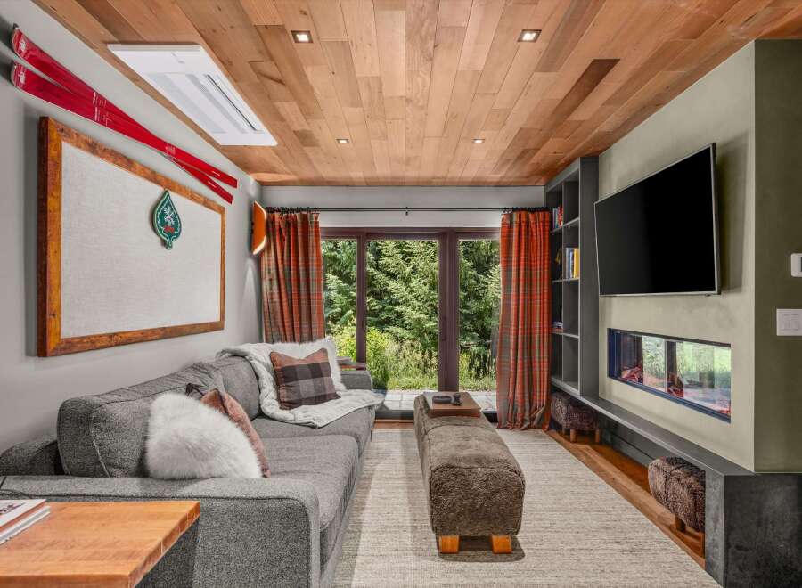 Experience mountain living in this cozy living room featuring a plush sectional sofa, a modern linear fireplace, and a large flat-screen TV.