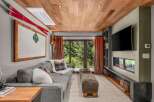 Experience mountain living in this cozy living room featuring a plush sectional sofa, a modern linear fireplace, and a large flat-screen TV.