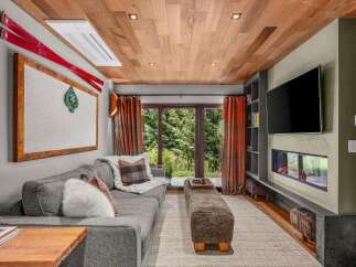 Experience mountain living in this cozy living room featuring a plush sectional sofa, a modern linear fireplace, and a large flat-screen TV.