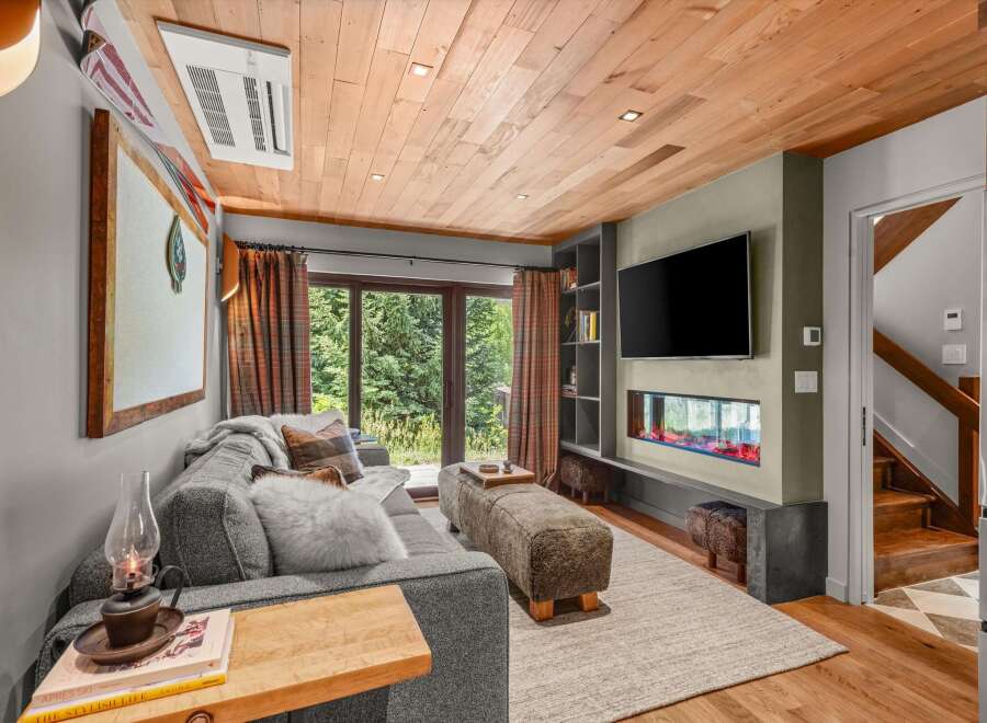 Experience cozy living in this mountain retreat, featuring a modern electric fireplace and a large flat-screen TV.