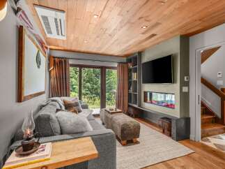 Experience cozy living in this mountain retreat, featuring a modern electric fireplace and a large flat-screen TV.