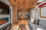 Experience modern mountain living in this stunning space featuring a sleek fireplace and a beautifully paneled wood ceiling.