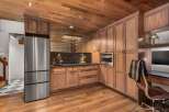 Experience luxury and functionality in this stunning kitchen featuring rich walnut cabinetry and a sleek stainless steel refrigerator.
