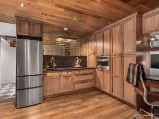 Experience luxury and functionality in this stunning kitchen featuring rich walnut cabinetry and a sleek stainless steel refrigerator.