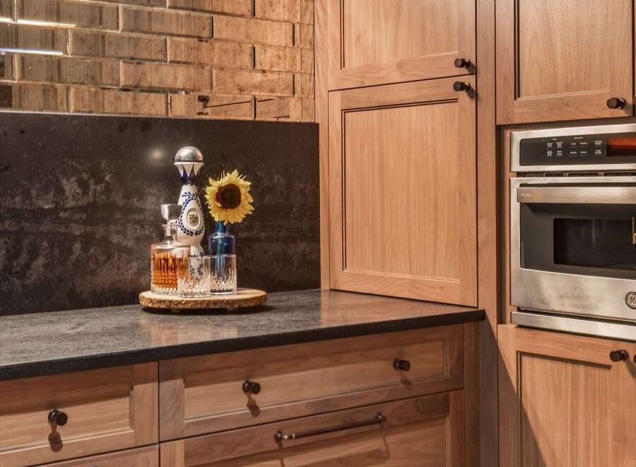 Experience sophisticated entertaining in this modern kitchen, featuring rich walnut cabinetry and a striking mirrored subway tile backsplash.