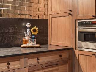 Experience sophisticated entertaining in this modern kitchen, featuring rich walnut cabinetry and a striking mirrored subway tile backsplash.