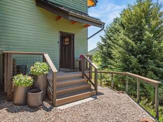 Welcome guests to this charming home with a beautifully maintained entrance featuring a covered porch and a set of wooden stairs leading to the front door.