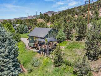 Experience serene mountain living in this charming green home nestled amongst mature trees.