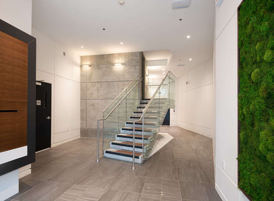 Experience modern living with this stunning interior featuring a sleek staircase with glass railings and wood accents.
