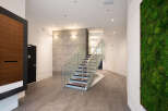 Experience modern living with this stunning interior featuring a sleek staircase with glass railings and wood accents.