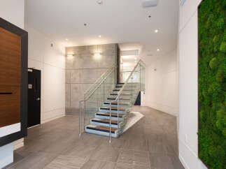 Experience modern living with this stunning interior featuring a sleek staircase with glass railings and wood accents.