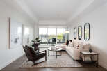 Experience modern living in this bright and airy living room, featuring a plush sectional sofa and a stylish leather armchair.