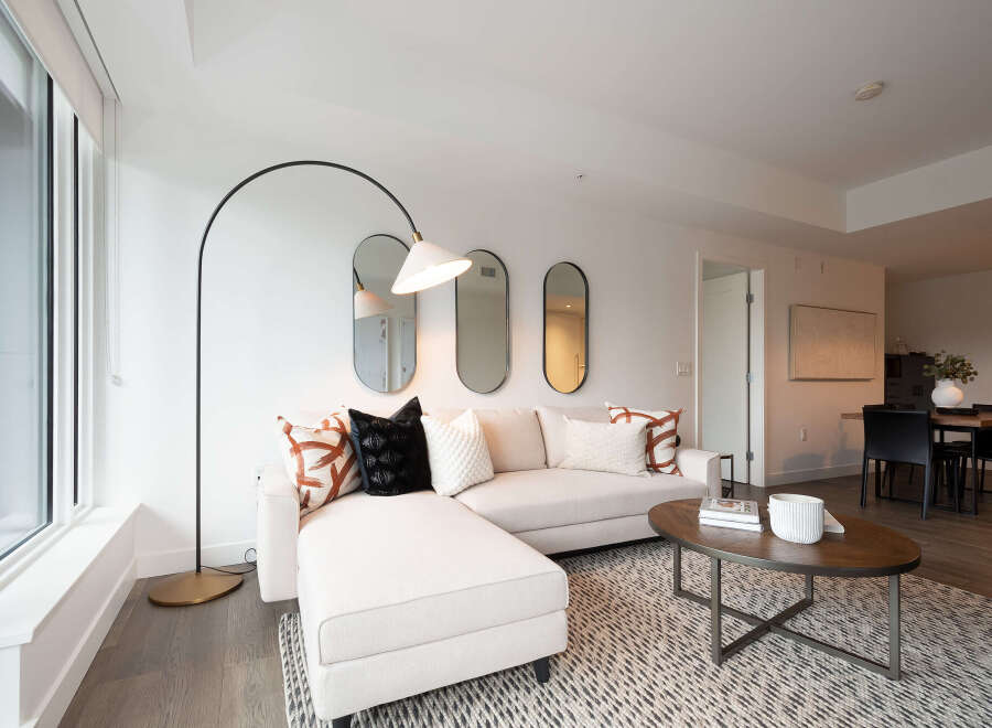 Experience modern living in this bright and airy living space, featuring a comfortable sectional sofa adorned with stylish accent pillows.