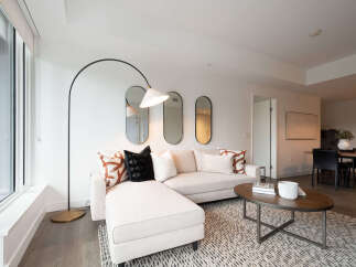 Experience modern living in this bright and airy living space, featuring a comfortable sectional sofa adorned with stylish accent pillows.