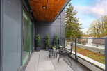Enjoy your morning coffee on this modern balcony, featuring sleek black furniture and elegant potted evergreens.