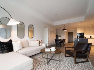 Experience modern living in this stylish open-concept apartment, featuring a spacious living area with a comfortable sectional sofa and a chic coffee table.