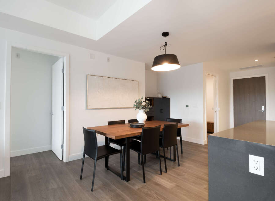 This modern dining area features a sleek wooden table with black chairs, perfect for intimate gatherings.