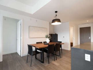 This modern dining area features a sleek wooden table with black chairs, perfect for intimate gatherings.