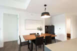 This modern dining room features a sleek wooden table with black chairs, illuminated by a stylish pendant light.